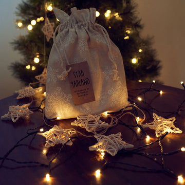 Rattan star garland with kit bag under a Christmas tree with fairy lights