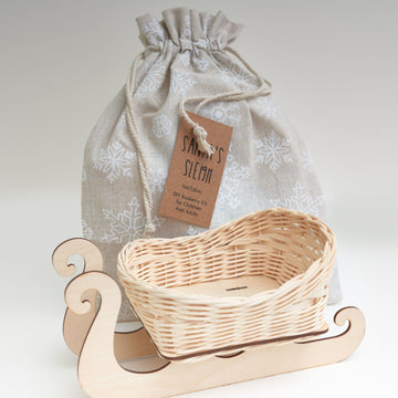 Finished rattan Santa's sleigh with wooden runners, beside its drawstring kit bag
